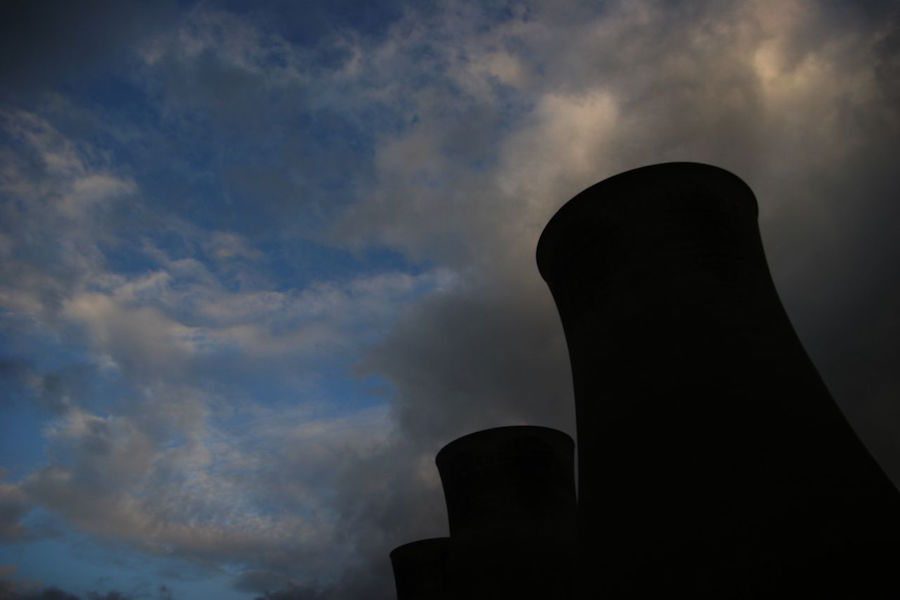 A power plant exhaust stack billowing smoke silhouetted against a dark sky