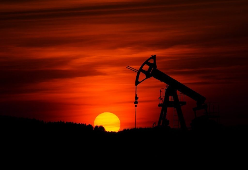 An oil well silhouetted against the setting sun