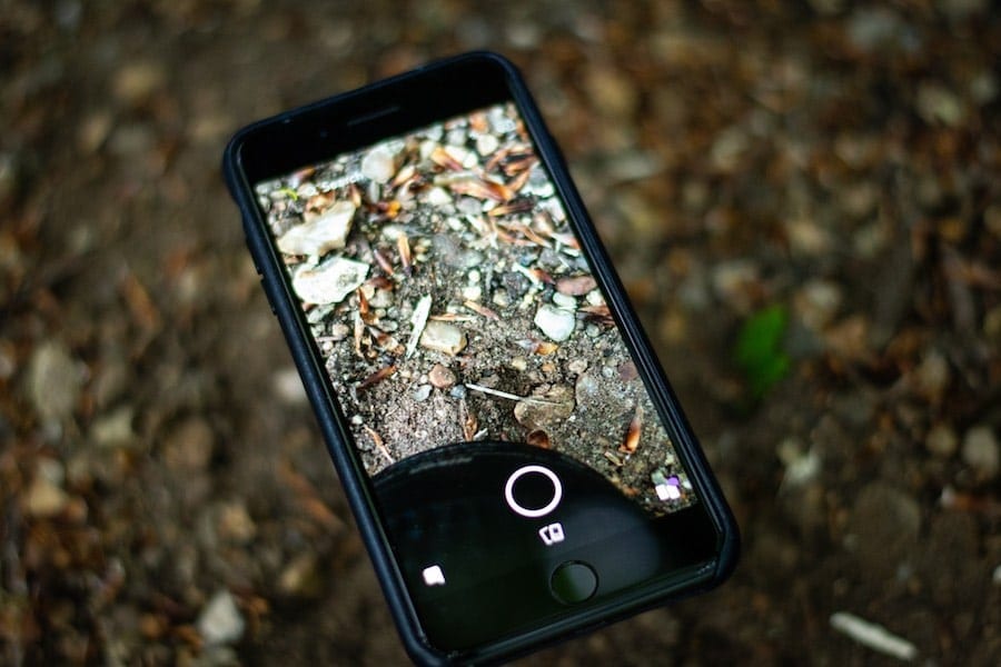 An old phone with a shattered screen sits in a landfill