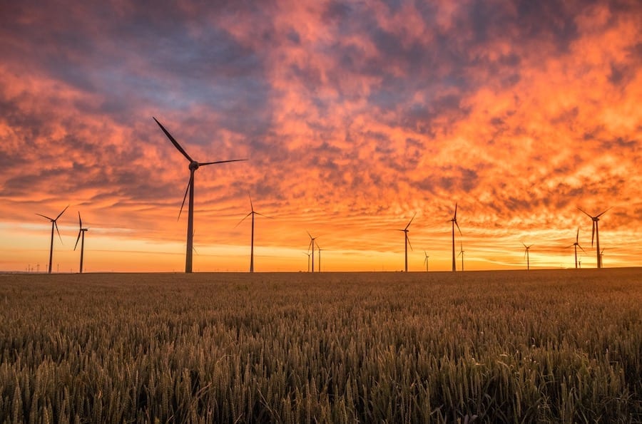 A wind farm sillouhetted against a vibrant sunset