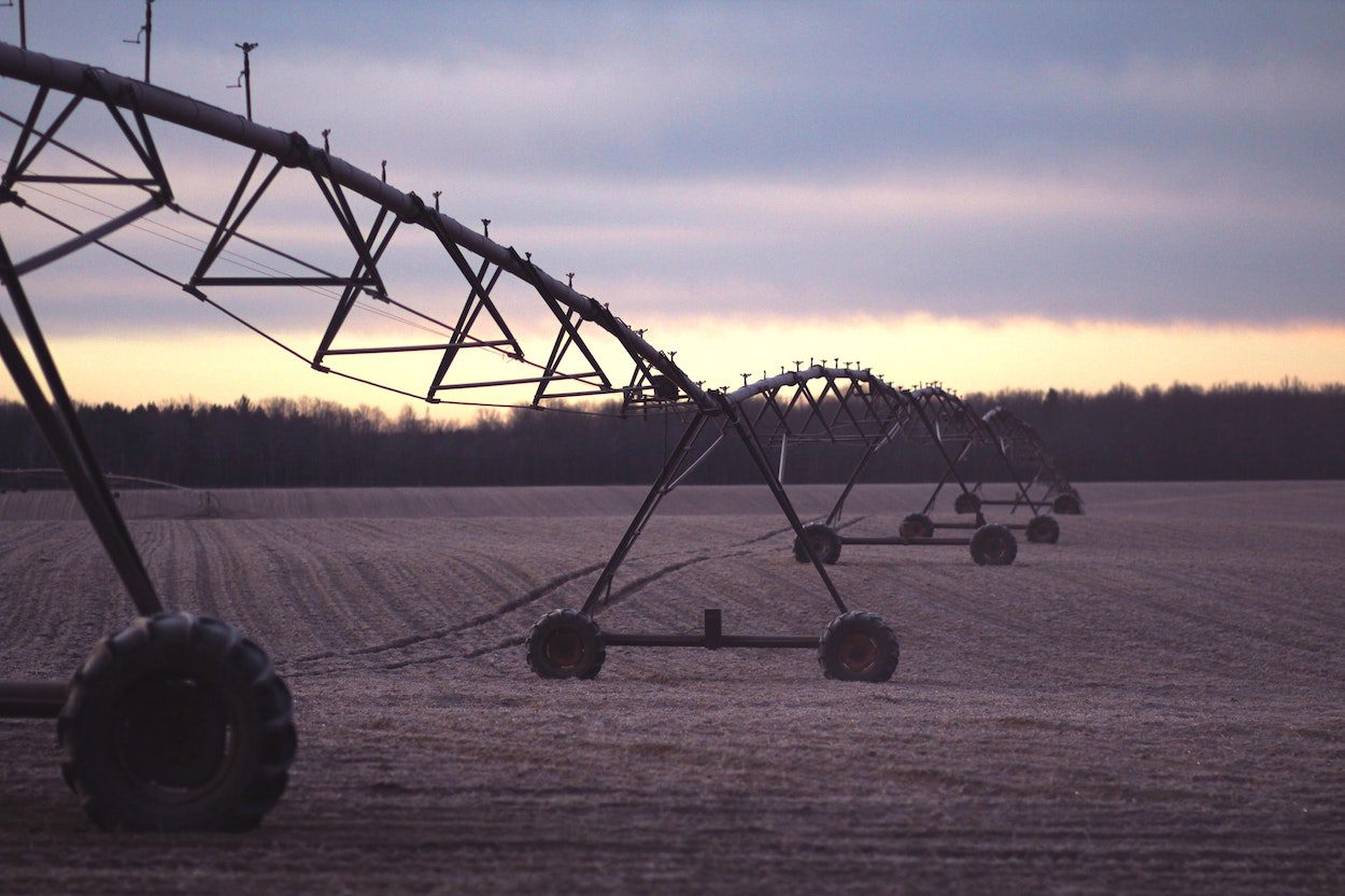 A long sprinkler irrigation system sits idle in a field