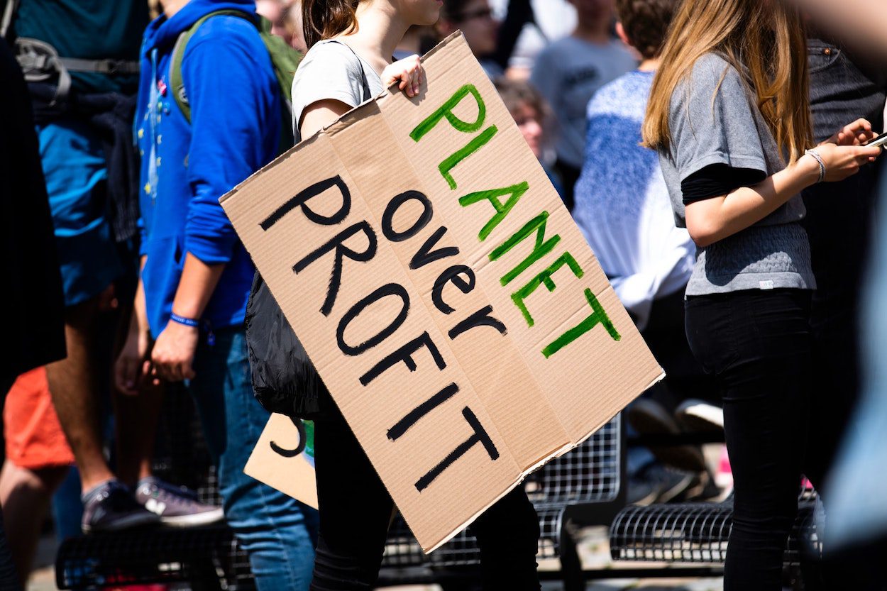 People gathered around a handmade sign saying "planet over profit"