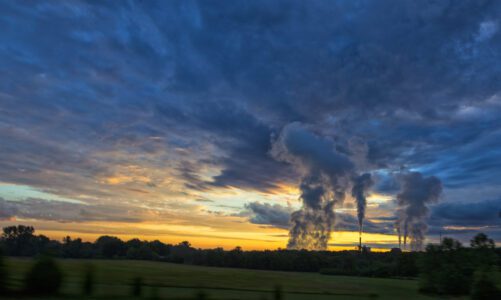Emission rise from a coal-fired coal power plant as the sun rises behind it.