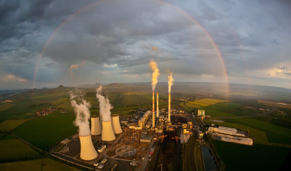 An aerial view of a power plant with a rainbow in the background