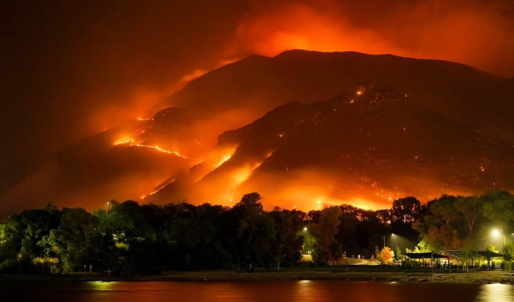 A wildfire rages in the hills behind a coastal town.