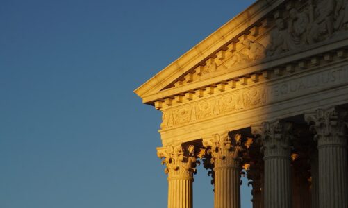 The columns and arch of the supreme court building in shadow and light.